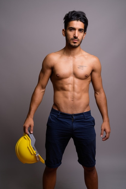 Young handsome Persian man construction worker shirtless