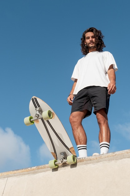 Young handsome skater standing at the top of the skate ramp