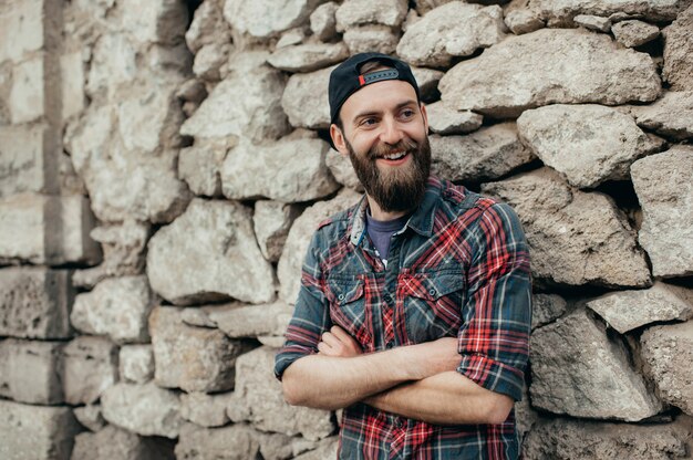 Young handsome smiling man with beard smiling over stone background