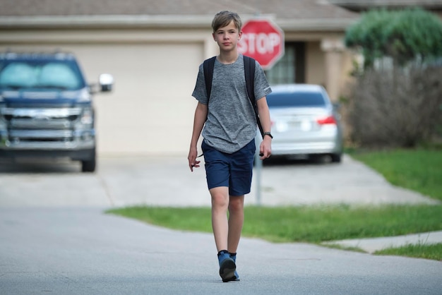 Young handsome smiling teenager boy with backpack happy going to school on sunny day