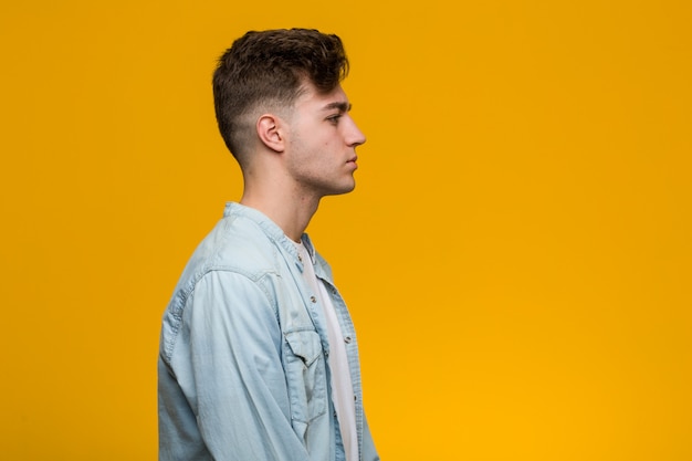 Young handsome student wearing a denim shirt gazing left, sideways pose.