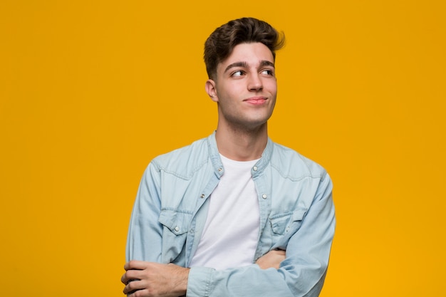 Young handsome student wearing a denim shirt smiling confident with crossed arms.