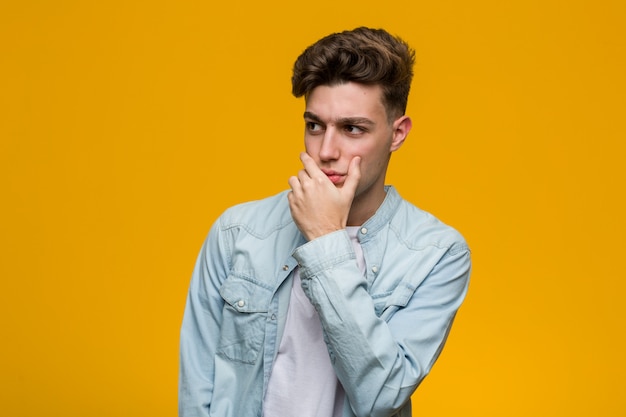 Young handsome student wearing a denim shirt thoughtful