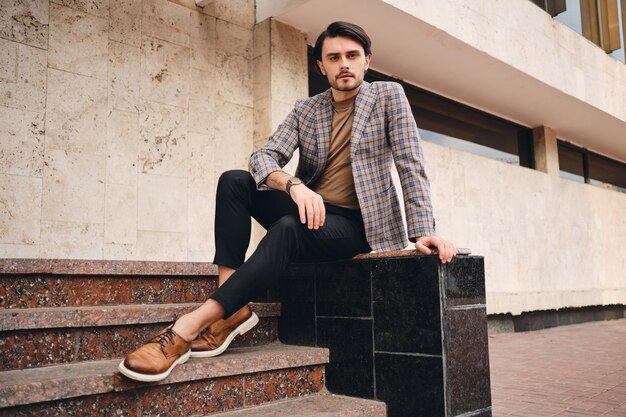 Photo young handsome stylish man in checkered jacket confidently looking in camera outdoor