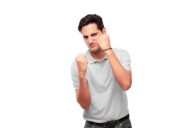 Young handsome tanned man with an angry, aggressive and menacing pose, ready for the fight, showing 