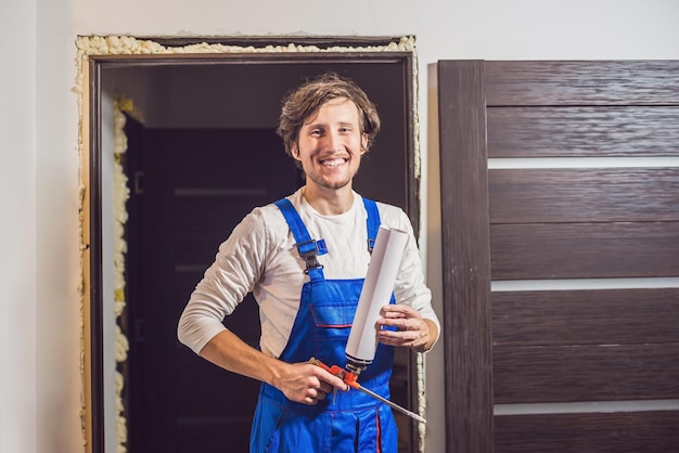 Young handyman installing door with an mounting foam in a room