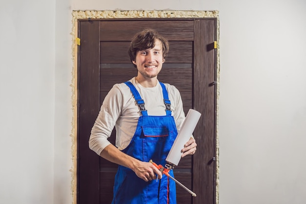 Young handyman installing door with an mounting foam in a room