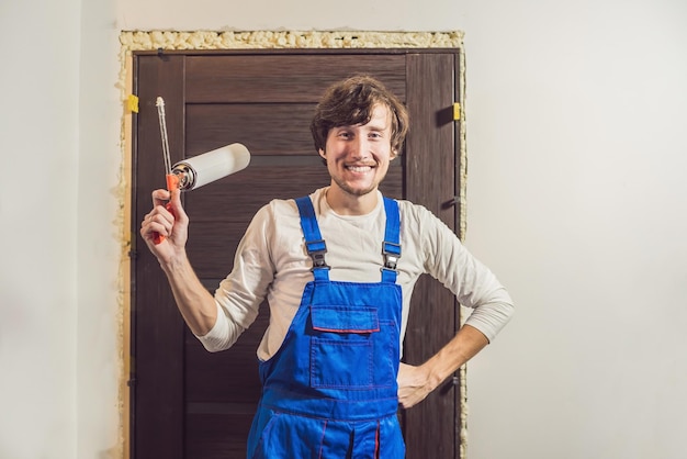 Young handyman installing door with an mounting foam in a room.