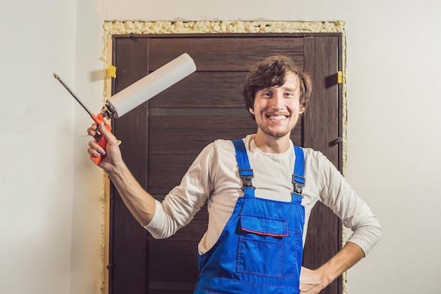 Young handyman installing door with an mounting foam in a room.