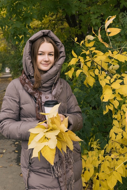 Young happiness beautiful girl with with coffee and yellow leaves Colors of autumn autumn season