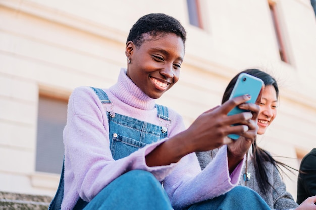 Young happy african american woman using smartphone Sharing media with friends with new app