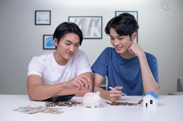 Young happy Asian gay couple saving money to buy a house LGBT men couple saving money for family and home