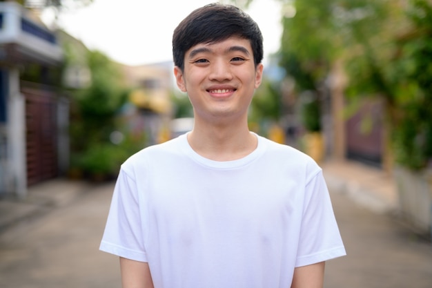 Young happy Asian man smiling in the street