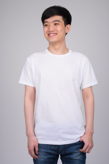 young happy Asian man smiling while thinking