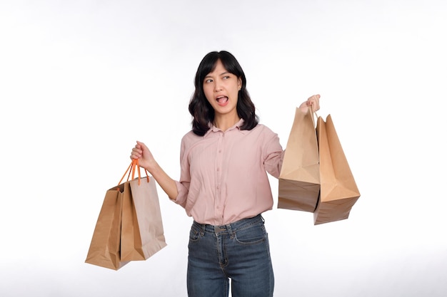 Young happy asian woman with casual shirt and denim jeans holding shopping paper bag isolated on white background