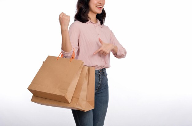 Young happy asian woman with casual shirt and denim jeans holding shopping paper bag isolated on white background