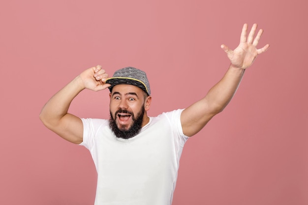 Young happy bearded football fan in cap celebrating. emotional man screaming on pink background