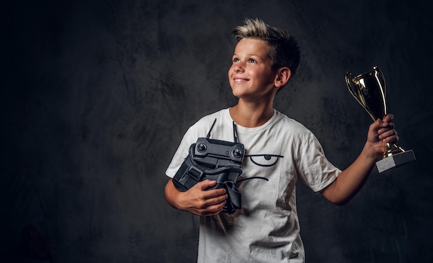 Young happy boy won the competition in virtual reality games and got the cup.