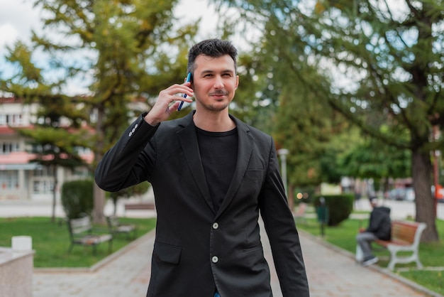 Young happy businessman talking on his phone outdoors