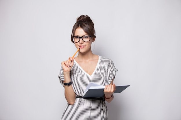 Young happy businesswoman makes some notes in notepad, isolated on white.