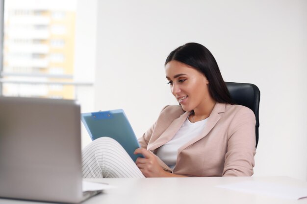 Young happy businesswoman in the office making notes in a notebook