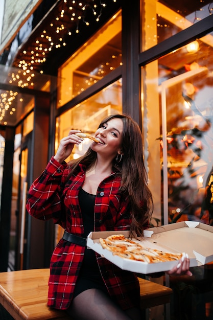 Young happy caucasian couple sitting at table enjoying freshly baked pizza i