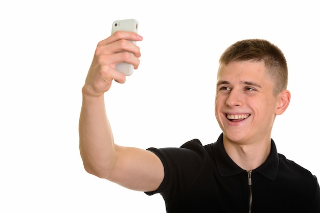 Young happy Caucasian man smiling and taking selfie with mobile