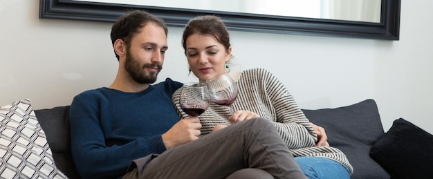 Young and happy couple drinking wine and relaxing at home