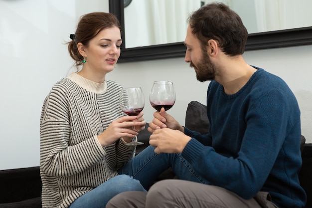 Young and happy couple drinking wine and relaxing at home