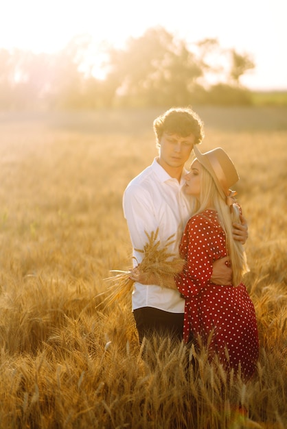 Young happy couple hugging on a wheat field on the sunset Enjoying time together