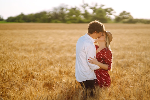 Young happy couple hugging on a wheat field on the sunset Enjoying time together