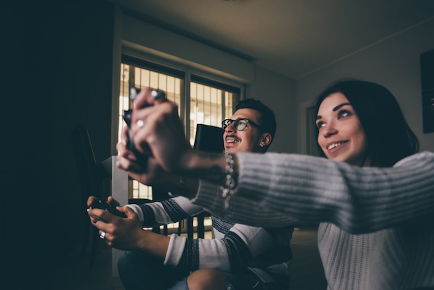 Young happy couple indoor at home playing videogame