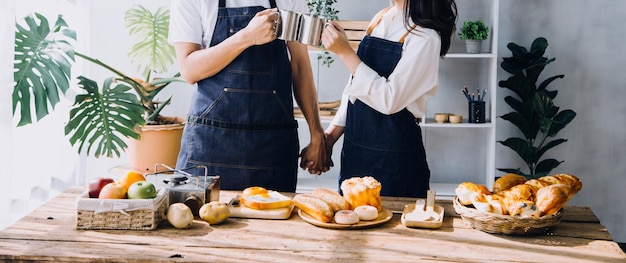 Young happy couple is enjoying and preparing healthy meal in their kitchen and reading recipes on the laptop