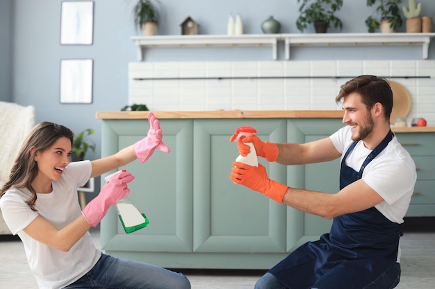 Young happy couple is having fun while doing cleaning at home.