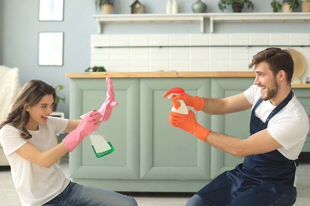 Young happy couple is having fun while doing cleaning at home.