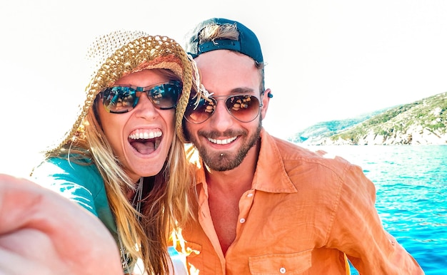 Young happy couple in love taking selfie at sailboat excursion with water camera