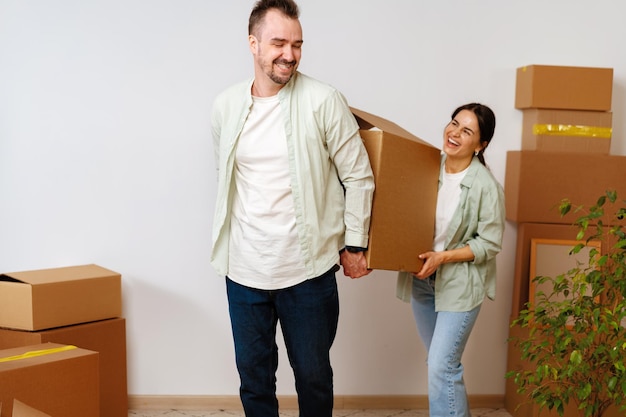 Young happy couple in room with moving boxes at new home