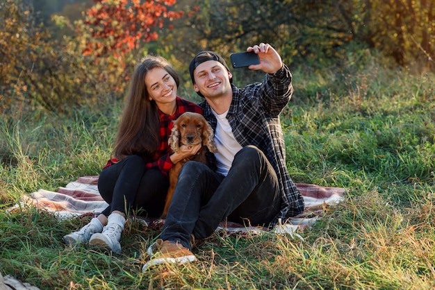 Young happy couple taking selfie using smartphone in the park.