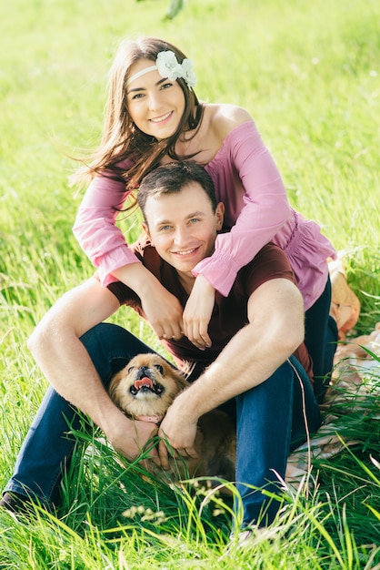 Young happy couple walking in park with a little doggy