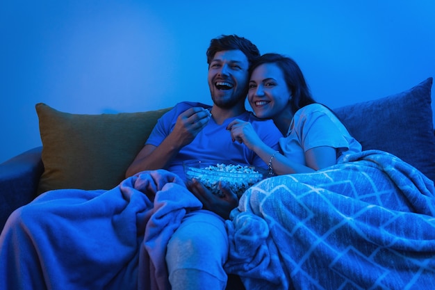 Young and happy couple watching comedy TV show at home