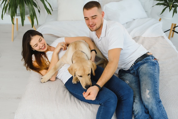 Young happy couple with dog sitting at home