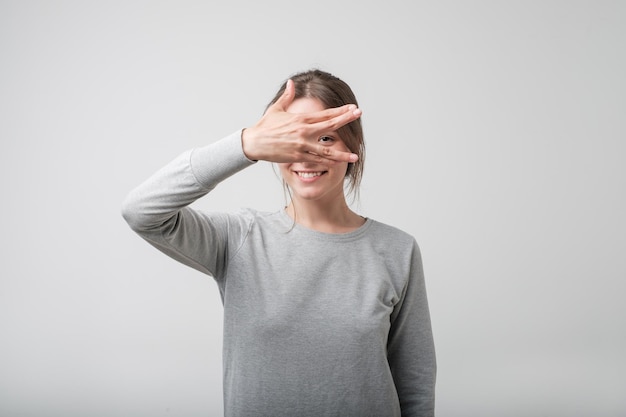 Young happy european female covering her face using hands