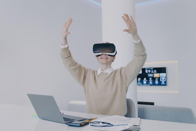 Young happy european woman in VR glasses is raising hands Concept of corporate innovation