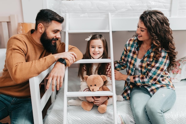 Young happy family buying new bed and mattress in big furniture store