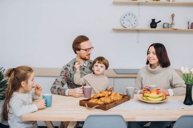 Young happy family with two kids having breakfast together