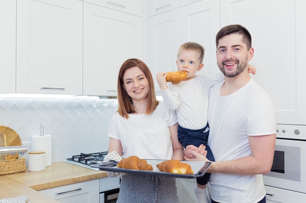 Young happy family with two young sons preparing breakfast together in their kitchen