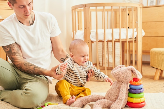 Young happy father is playing with the baby in the living room