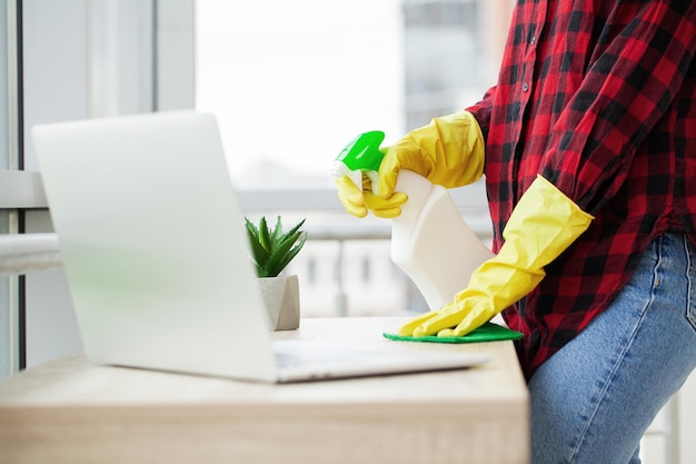 Young Happy Female Janitor Cleaning Wooden Desk With Rag In Office