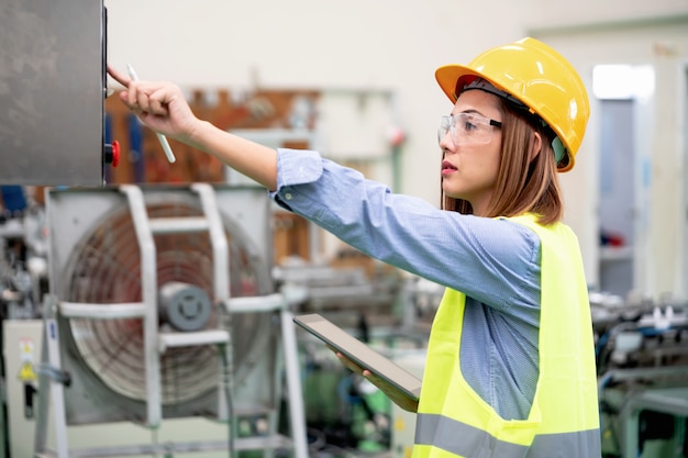 Young happy female worker in factory use tablet checking program before shipment. Inspection quality control