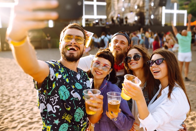 Young happy friends drinking beer and having fun at music festival together Friendship